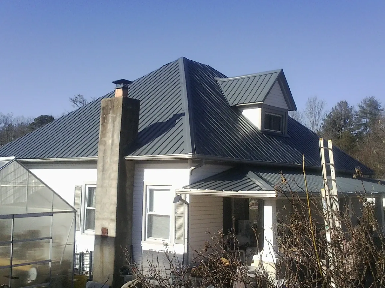 Dark blue standing seam metal roof on a white farmhouse with dormer — Slate & Tile Roof Repair by Roofing Brothers in Humboldt