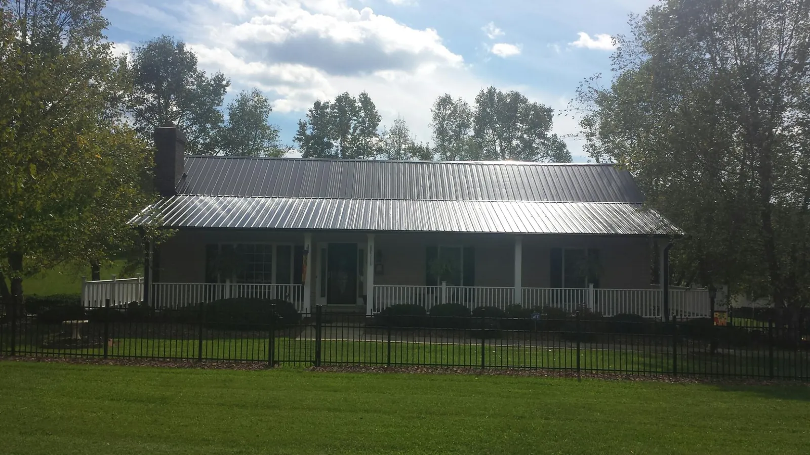 Gray metal roof on a brick ranch with a full width front porch — Gutter Guard Installation work by our crew in Humboldt