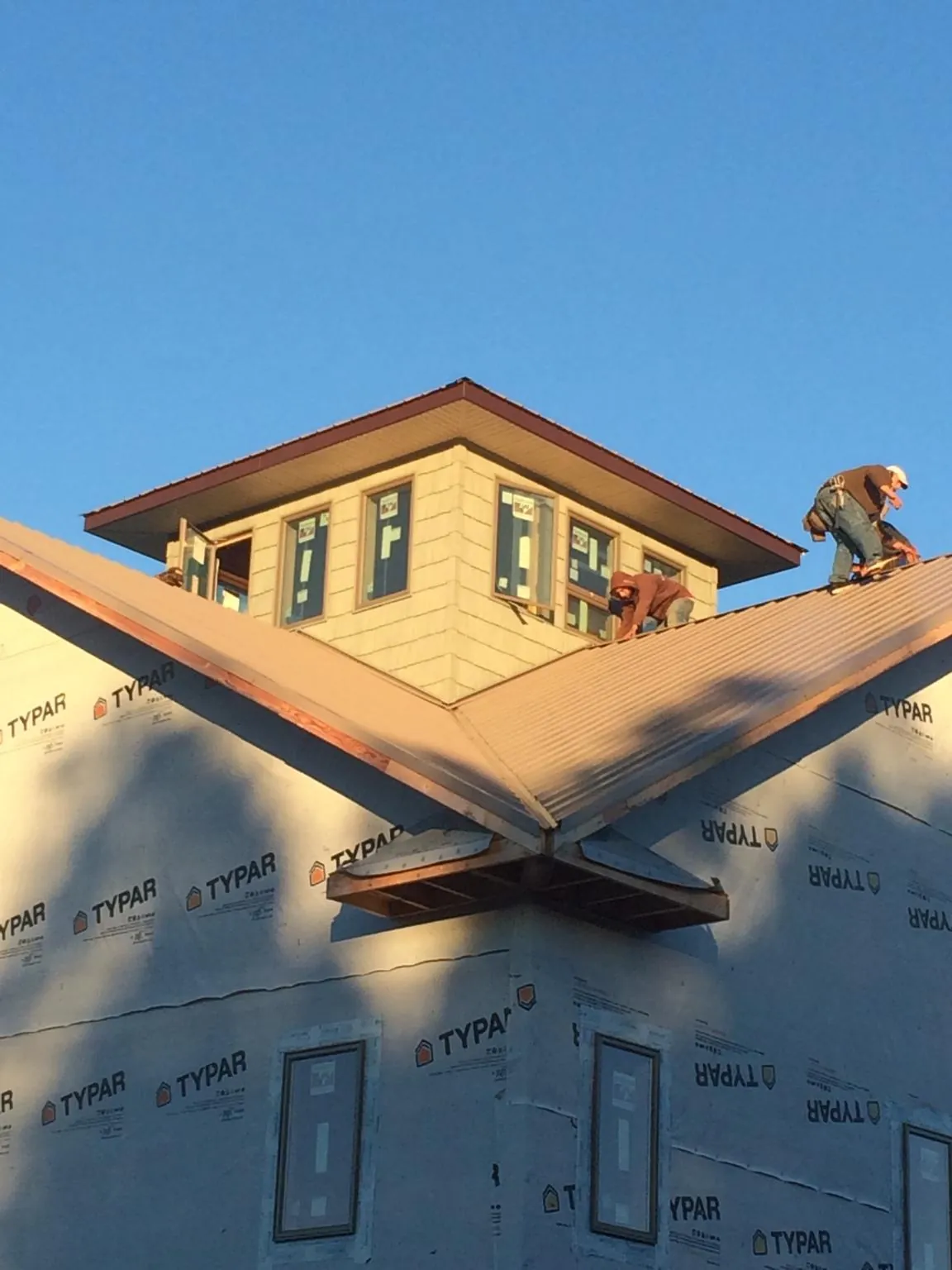 Roofers working around a rooftop cupola on a new metal roof at sunset — Roof Waterproofing in Humboldt by Roofing Brothers